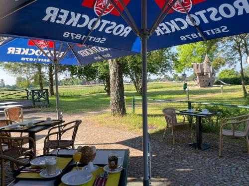 a table with a blue umbrella in a park at Ferienhotel Alter Bahnhof garni in Prerow