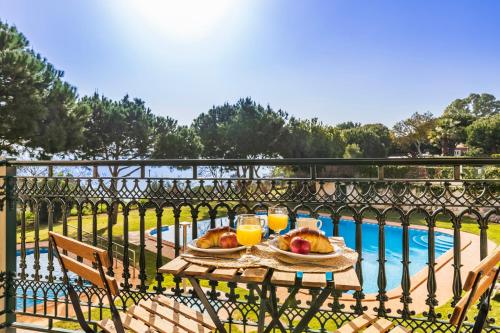 a table with two plates of fruit and orange juice next to a pool at Quinta Pedra Dos Bicos in Albufeira