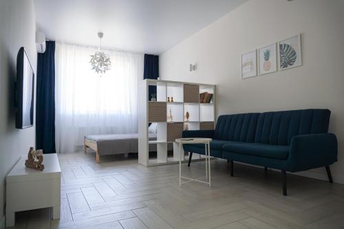 a living room with a blue couch and a bed at Arkadia apt in Odesa