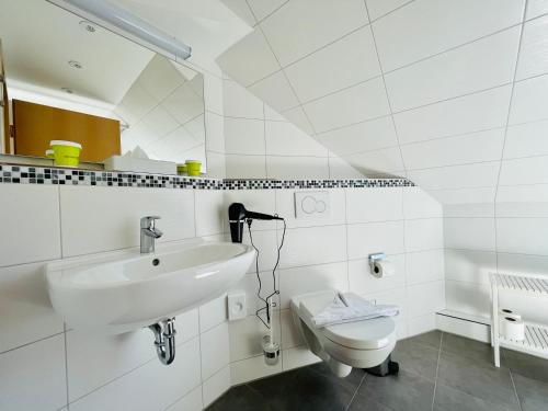a white bathroom with a sink and a toilet at Ferienhotel Alter Bahnhof garni in Prerow