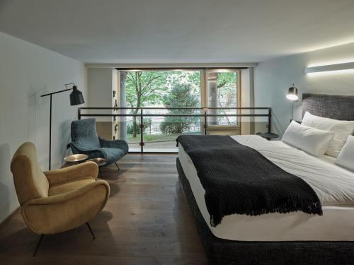 um quarto com uma cama, uma cadeira e uma janela em Parcloft em Merano