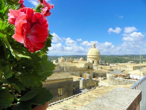a flower on a balcony with a view of a city at Cloris Guest House in Noto