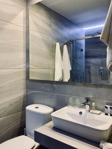 a bathroom with a sink and a toilet and a mirror at LUZ Vejer Hospedería in Vejer de la Frontera