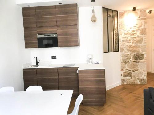 une cuisine avec des armoires en bois et un comptoir blanc dans l'établissement Buffa Résidence, à Nice