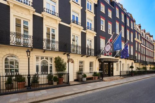 a row of buildings on a street with flags at The Mayfair Townhouse - an Iconic Luxury Hotel in London
