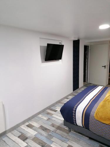 a bedroom with a bed and a flat screen tv on the wall at Chambre privé chez Chris in Villers-Semeuse