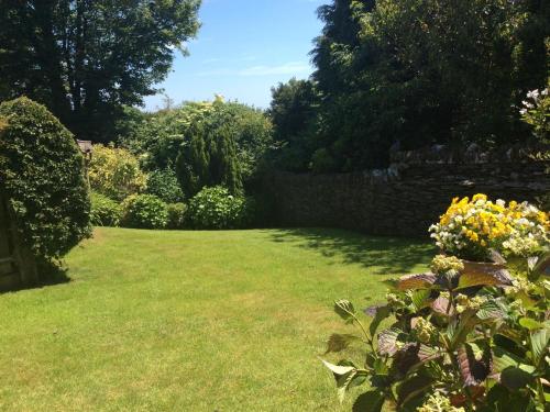 a garden with a wall and some flowers at Frogwell in Strete