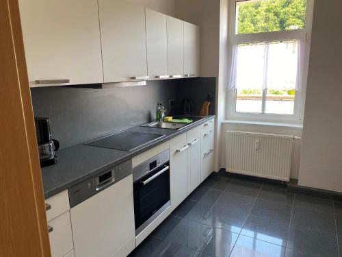 a kitchen with white cabinets and a sink and a window at An der Porzellan-Manufaktur Pension in Meißen