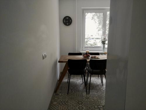 a dining room table with chairs and a clock on the wall at Homely apartment in Kėdainiai in Kėdainiai