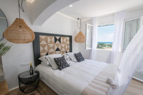 Schlafzimmer mit einem Bett mit weißer Bettwäsche und Kissen in der Unterkunft Divine Naxos Villa in Plaka