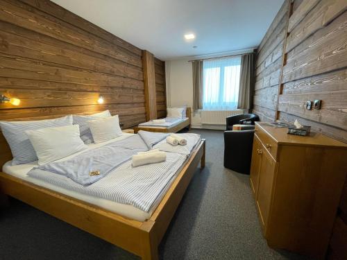 1 dormitorio con 1 cama grande y pared de madera en Hotel Kristian en Kubova Huť