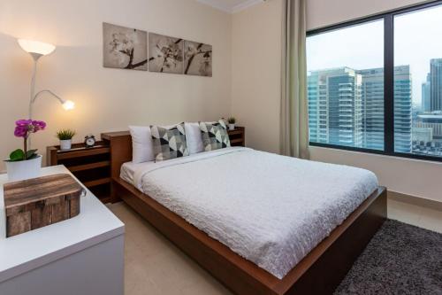 a bedroom with a bed and a large window at HiGuests - Modern Apt in Dubai Marina With Pool and Gym in Dubai