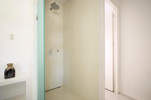 a white bathroom with a glass shower door at Wise Luxury Suites in Kithnos