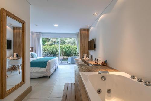 ein Badezimmer mit einer Badewanne und ein Schlafzimmer mit einem Bett in der Unterkunft Live Hotel Boutique (Adults only) in Punta del Este