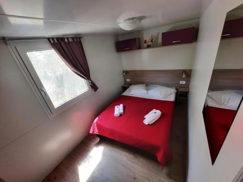 a small room with a red bed and a window at Kamp Rujno in Starigrad