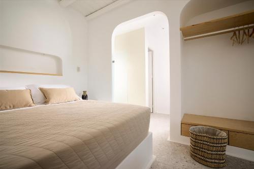a white bedroom with a bed and a chair at Wise Luxury Suites in Kithnos