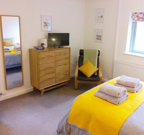 1 dormitorio con cama amarilla y espejo en Cherry Cottage - Perfect base for two in beautiful Pembrokeshire, en Begelly