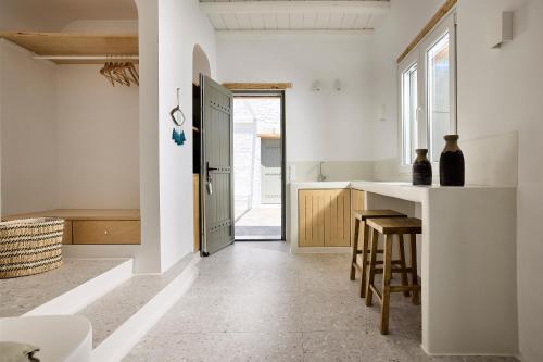 a kitchen with white walls and a counter and stools at Wise Luxury Suites in Kithnos