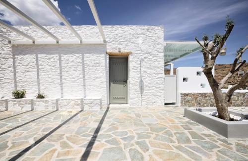 a white building with a door and a tree at Wise Luxury Suites in Kithnos