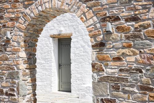 an arch in a stone wall with a door at Wise Luxury Suites in Kithnos