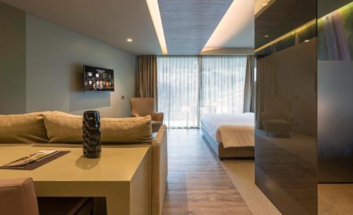 a living room with a couch and a bed in a room at Saccharum - Resort and Spa - Savoy Signature in Calheta