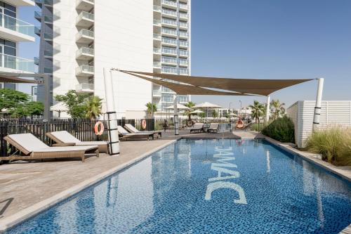 a swimming pool with chaise lounges and a hotel at Radisson Dubai Damac Hills in Dubai