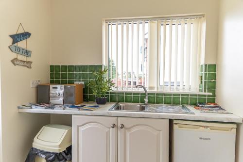 a kitchen with a sink and a window at The Hawthorns, Buncrana by Wild Atlantic Wanderer in Buncrana