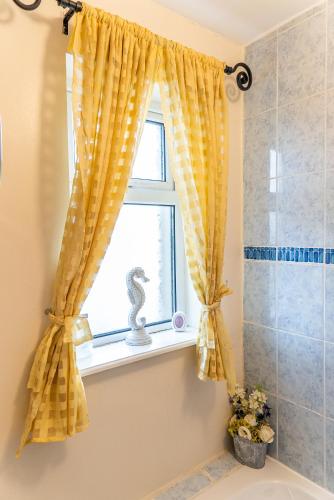 a window with a yellow curtain in a bathroom at The Hawthorns, Buncrana by Wild Atlantic Wanderer in Buncrana