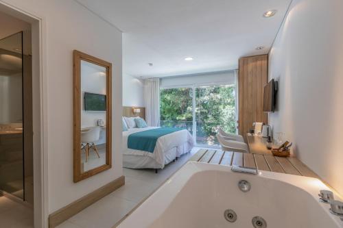 a bathroom with a bed and a tub and a bedroom at Live Hotel Boutique (Adults only) in Punta del Este