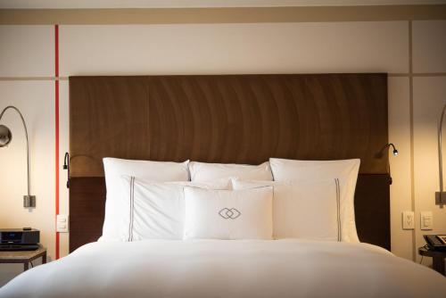 a white bed with white pillows and a brown headboard at Sofitel Bogota Victoria Regia in Bogotá
