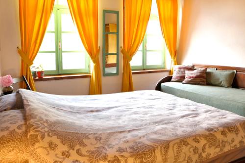 a bedroom with orange curtains and a bed and a couch at Stone City Hostel in Gjirokastër