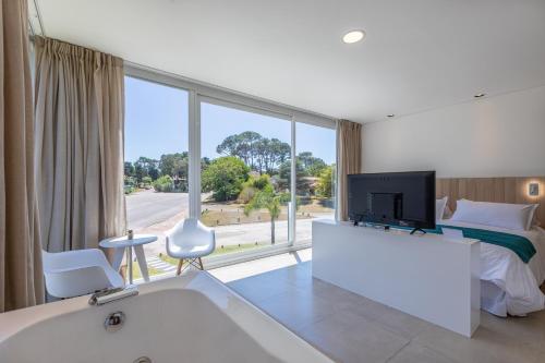 a bedroom with a tub and a bed and a tv at Live Hotel Boutique (Adults only) in Punta del Este