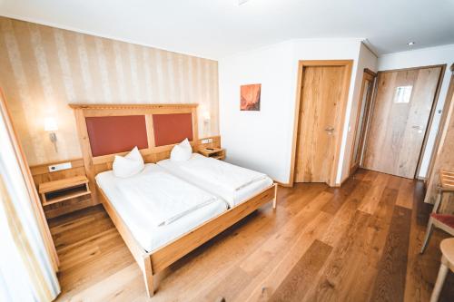 a bedroom with a large white bed and wooden floors at Hotel & Gasthof Löwen in Ulm