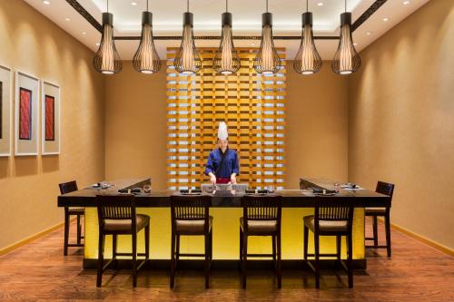 a dining room with a table and a statue of a chef at Wanda Realm Harbin Hotel in Harbin