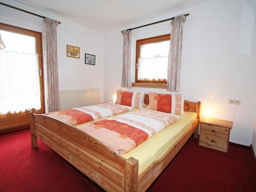 sypialnia z drewnianym łóżkiem i 2 oknami w obiekcie Apartment Sonnenheim-1 by Interhome w Mayrhofen