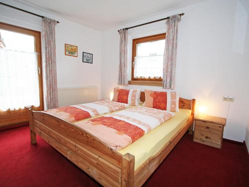 1 dormitorio con 1 cama de madera y 2 ventanas en Apartment Sonnenheim-1 by Interhome, en Mayrhofen