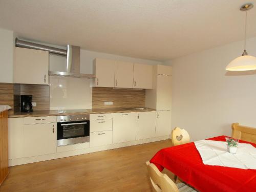 a kitchen with white cabinets and a table with a red blanket at Holiday Home Hauser by Interhome in Mayrhofen