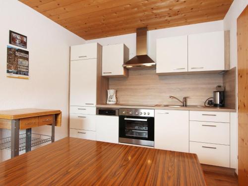 cocina con armarios blancos y mesa de madera en Apartment Gottfried-1 by Interhome, en Hainzenberg