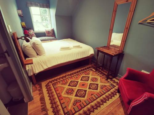 a bedroom with a bed with a mirror and a rug at Comrie Croft in Crieff