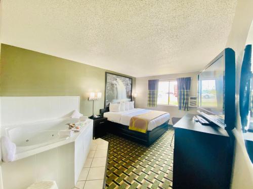 um quarto de hotel com uma cama e uma banheira em Super 8 Grand Rapids City Center em Wyoming
