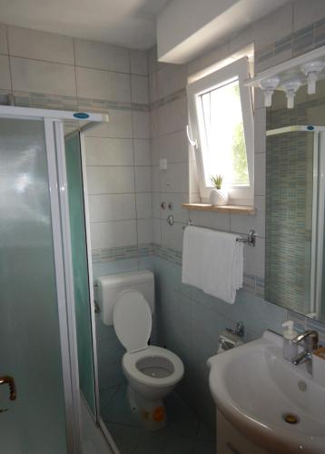a bathroom with a toilet and a sink and a window at Perla Apartments in Poreč