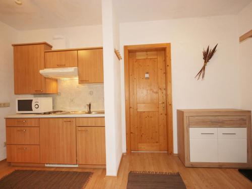 an empty kitchen with wooden cabinets and a door at Apartment Vallis Bella by Interhome in Langesthei