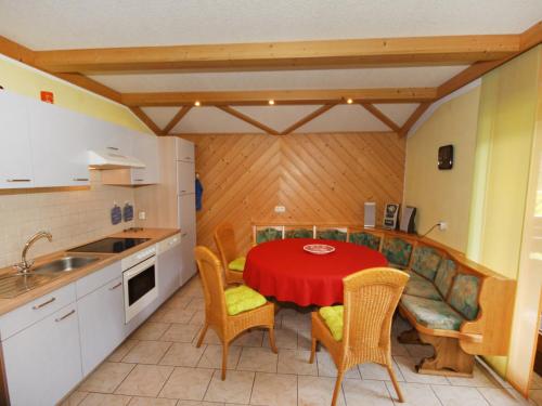 ドルフガシュタインにあるApartment Haus Harlander by Interhomeの赤いテーブルと椅子付きのキッチンが備わります。