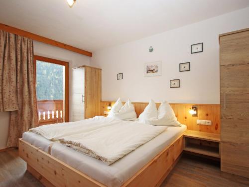 ein Schlafzimmer mit einem großen Bett und einem Fenster in der Unterkunft Apartment Werner by Interhome in Pettneu am Arlberg