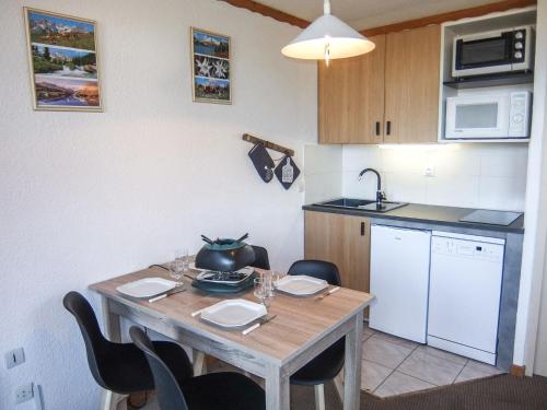 a kitchen with a wooden table with chairs and a sink at Apartment La Boédette-1 by Interhome in Les Menuires