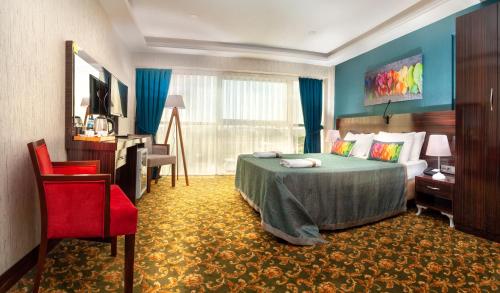 une chambre d'hôtel avec un lit et un fauteuil rouge dans l'établissement MARINN DELUXE HOTEL, à Yalova
