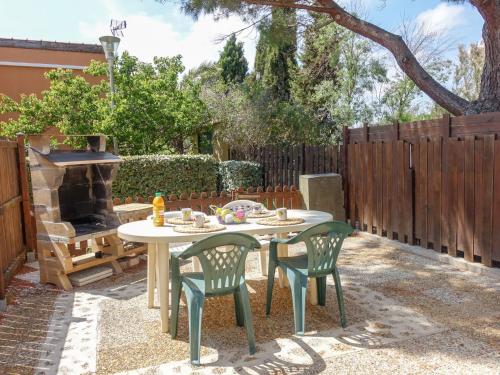 a patio with a table and chairs and a fireplace at Holiday Home Les Amandines-3 by Interhome in Gruissan