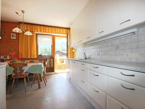 cocina con armarios blancos, mesa y comedor en Apartment Arlberg by Interhome, en Sankt Anton am Arlberg