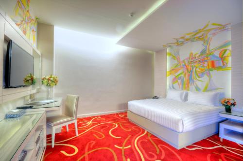 a bedroom with a bed and a desk and a tv at One One Bangkok in Bangkok