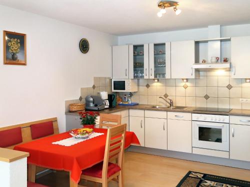 a kitchen and dining room with a red table and chairs at Apartment Bergkristall by Interhome in Spiss